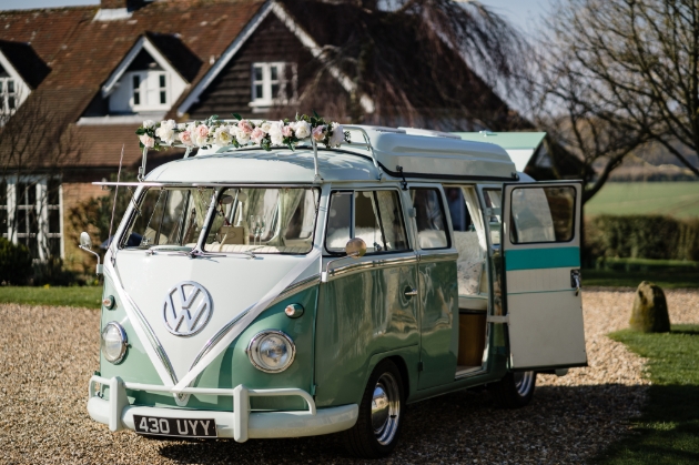 Green and white vintage VW camper dressed with flowers for a wedding