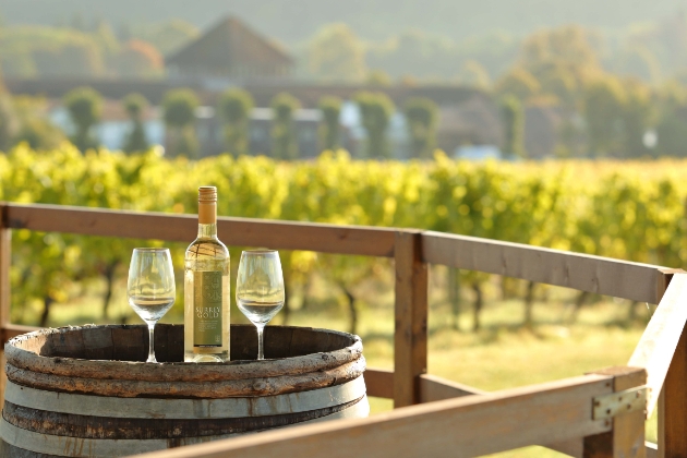 A bottle of Surrey Gold English wine sits atop a wine cask at Denbies Wine Estate