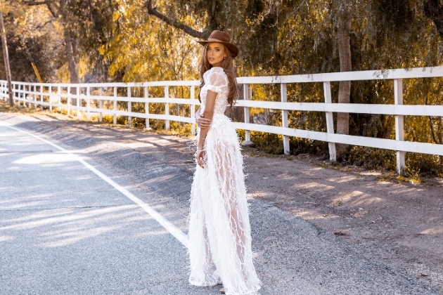 Bride in a cowboy hat in the road wearing a wedding dress