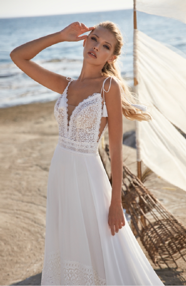 Model is on the beach wearing a wedding dress 
