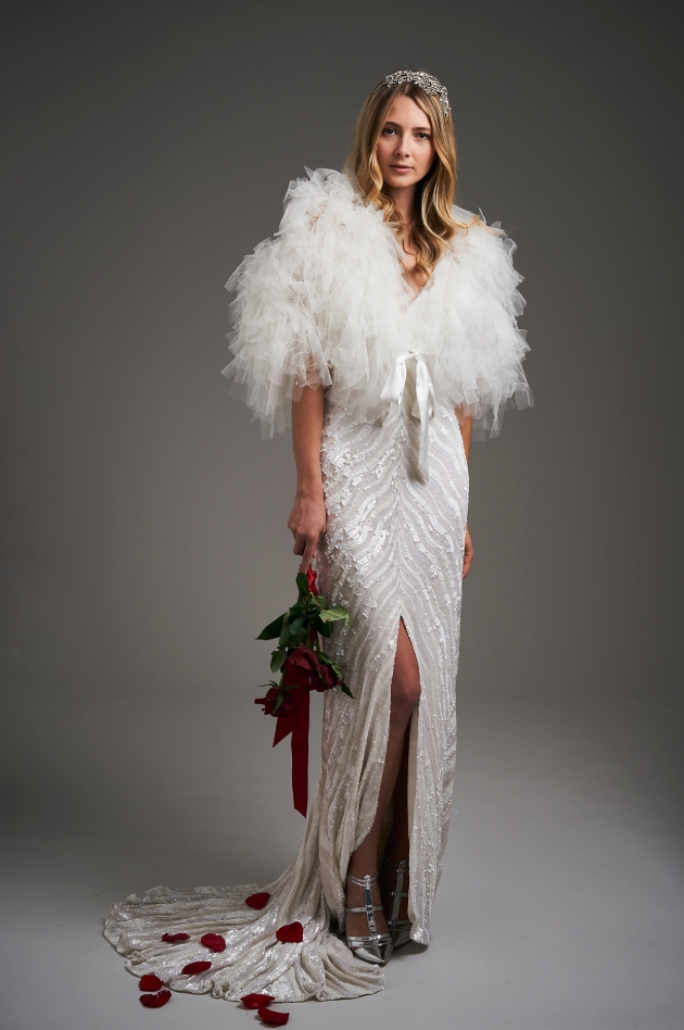 Model wears Art Deco style dress with tulle jacket and holding flowers