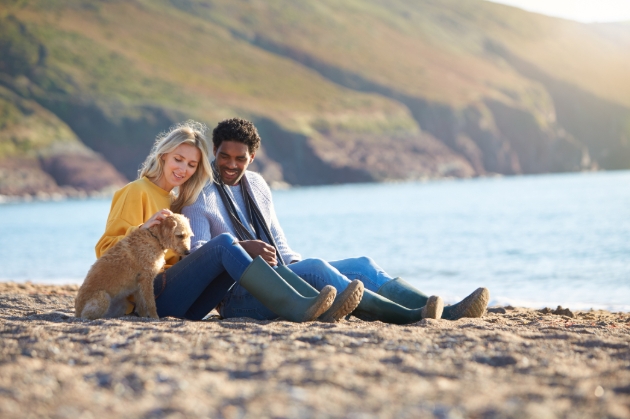 happy couple on the beach with their dog hills in the background