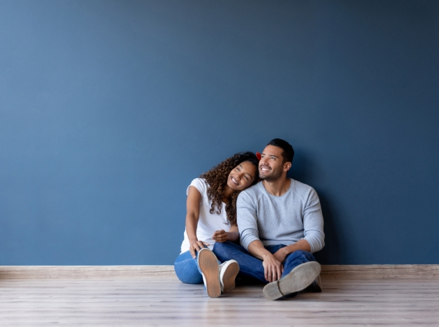 couple sitting on floor together against a wall in a house