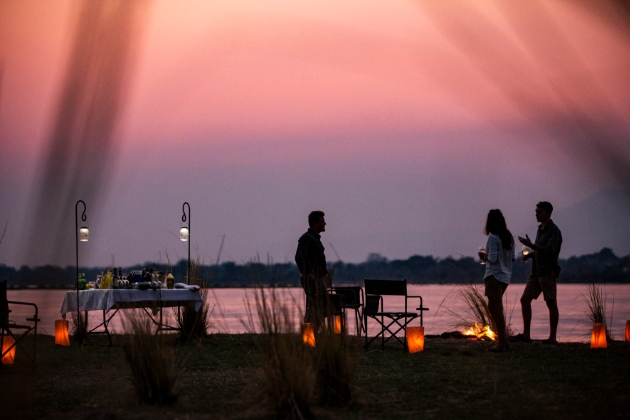 couple having dinner with a friend outside at night by waterhole