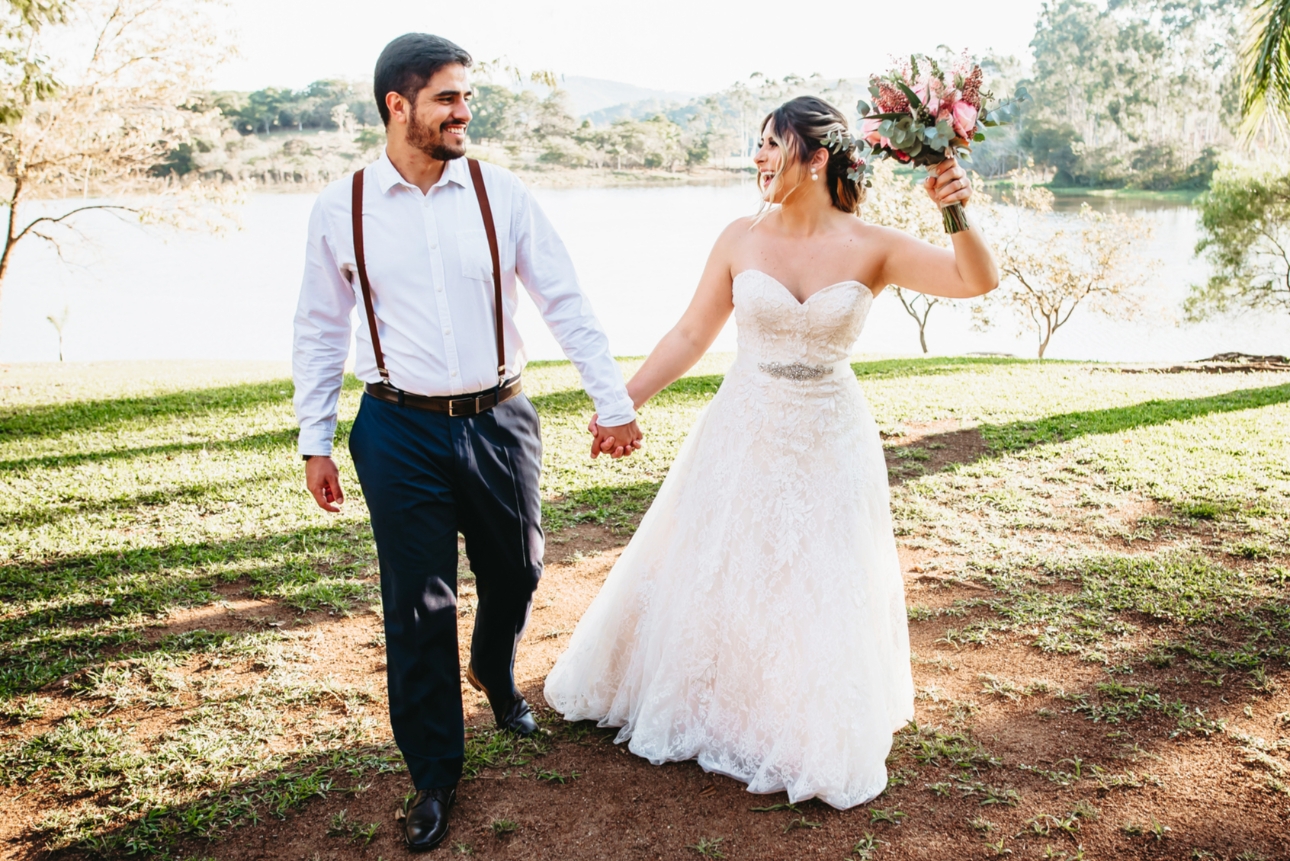 Couple tying in bride and groom outfits outside by lake