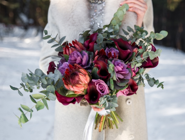 bride in stone holding drak red bouquet