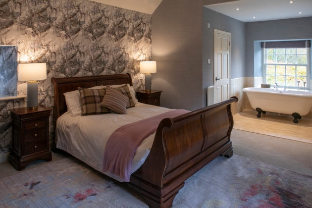 image of a wooden bed in a newly refurbished bedroom with bathtub