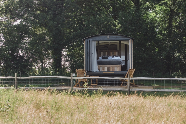 sheperds hut in the field, doors open with table and chairs outside on sunny day