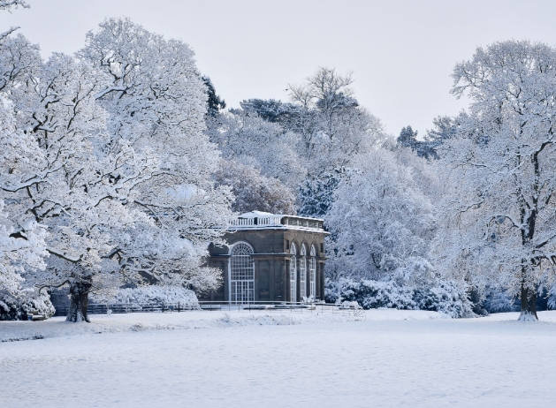 temple in middle of lawn surrounded by trees in snow