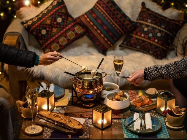 table of Christmas food and decor with two people using a fondu