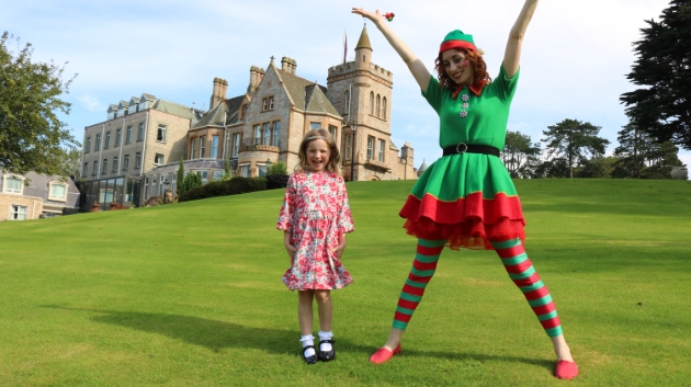 UK woman dressed as elf with child with hotel in the background
