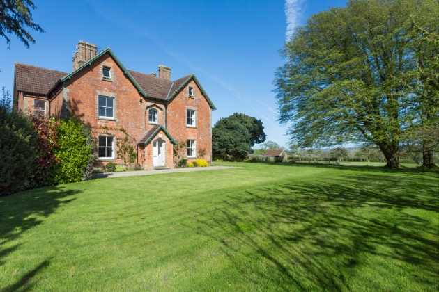 red brick house on the edge of a large green lawn