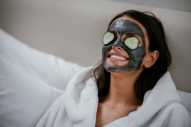 Woman wearing a face mask with cucumber slices over her eyes.