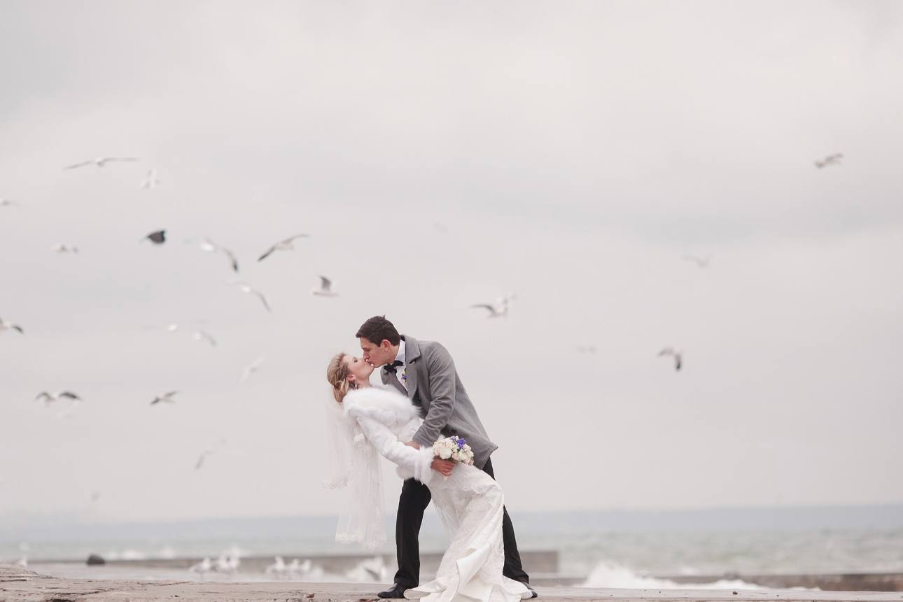 couple in the winter in wedding clothes kissing on a pier