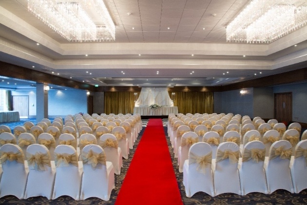 ceremony room of hotel red carpet white chairs and gold sashes 