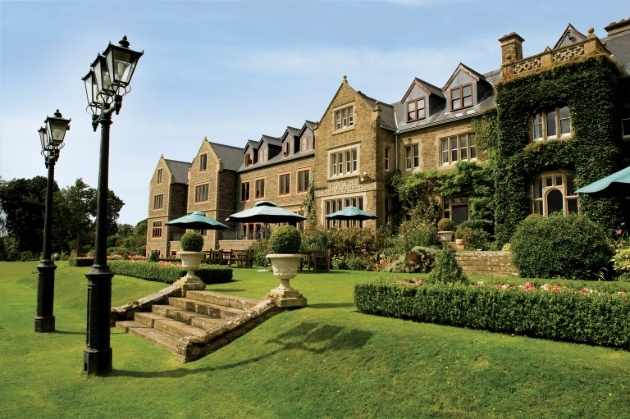 hotel covered in ivy, with terrace and tables and chairs 