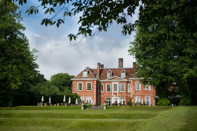 red brick hotel with lawns and terrace and tables and chairs