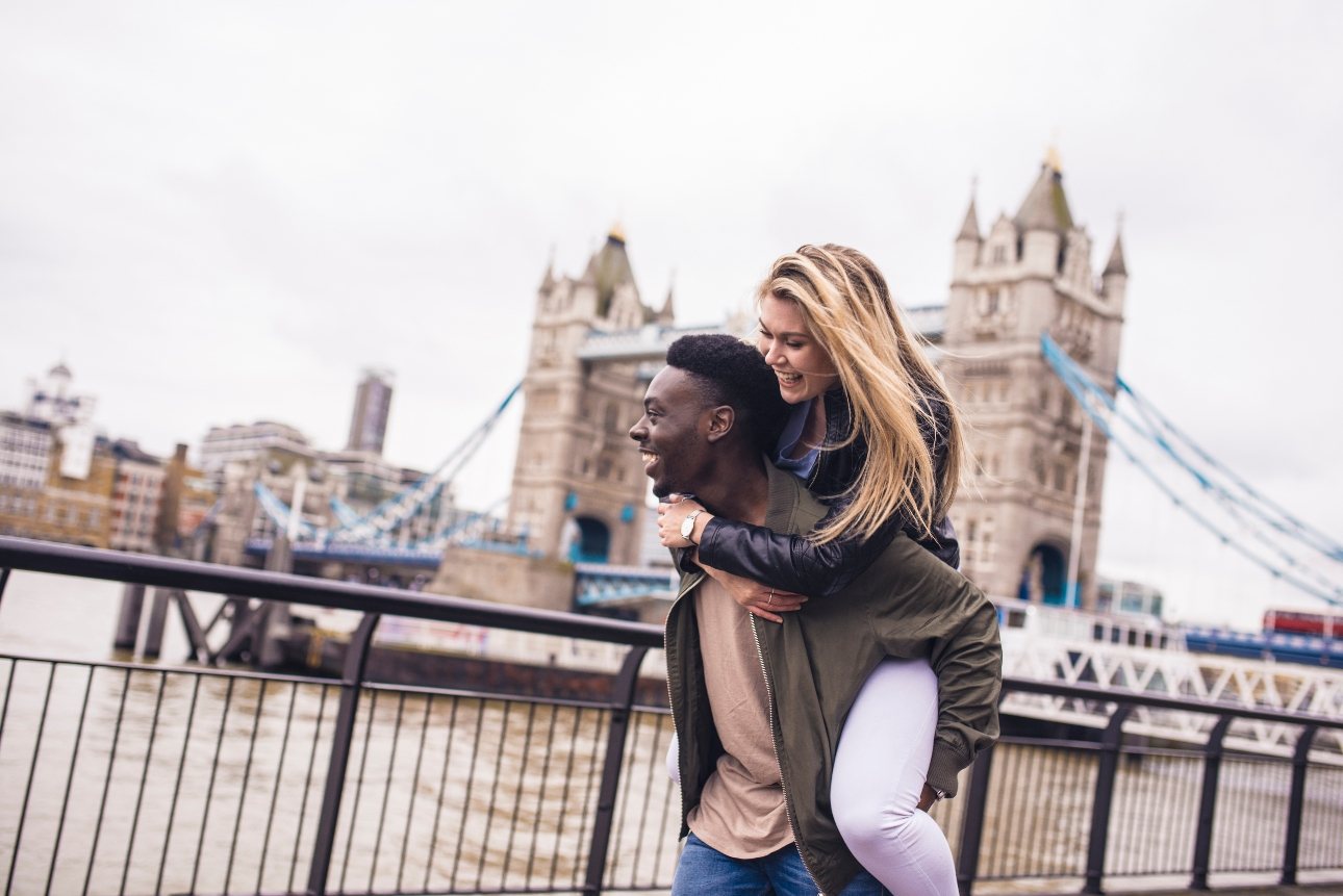 couple walking by thames london bridge in background 