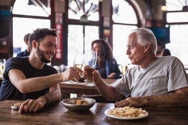 father and son sitting in a bar cheersing 