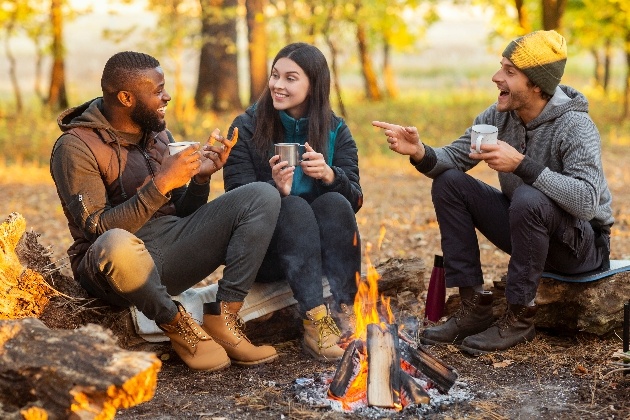 men and women round a camp fire