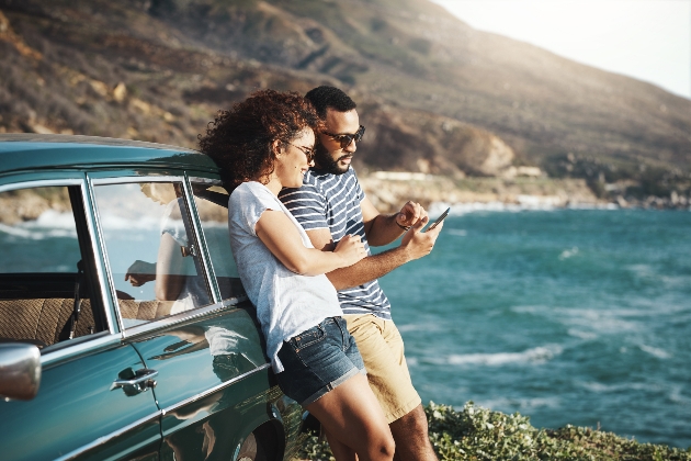 couple on phone by car on cliff