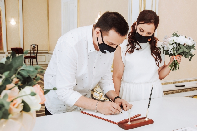 wedding couple signing register with masks on 