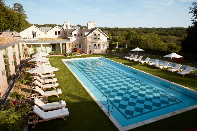 swimming pool in manicured garden with loungers on the grass