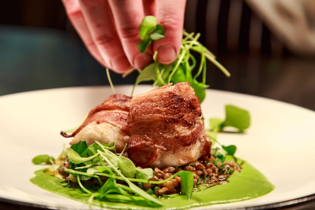 salad on a plate with a hand adding garnish