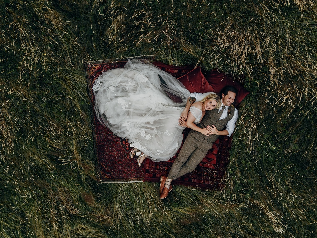 Couple lay on carpets in field
