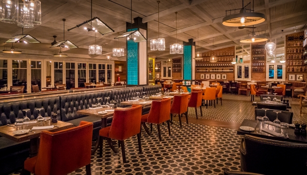 restaurant with checked floor, orange chairs and leather booth style seating