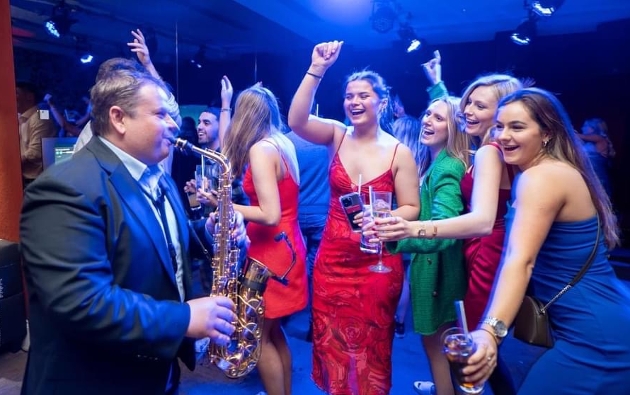 DJ V playing saxaphone to a group of partygoers