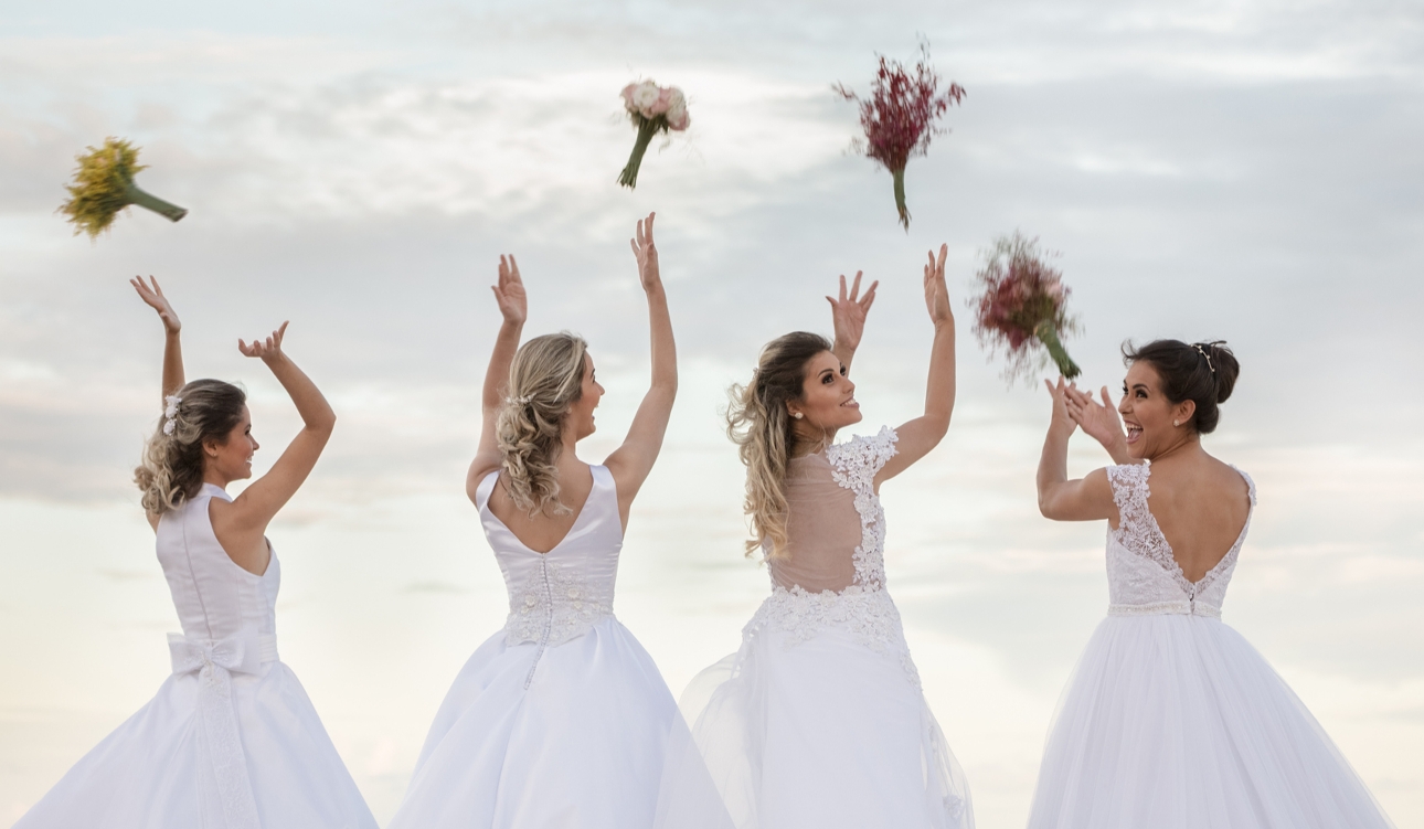 four brides all chucking their bouquets in the air