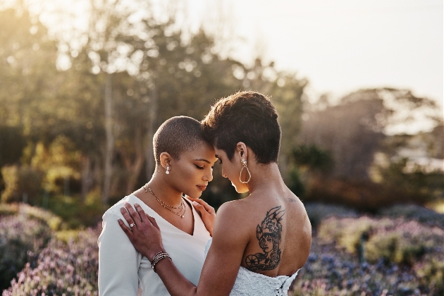 two brides stand in a field embracing