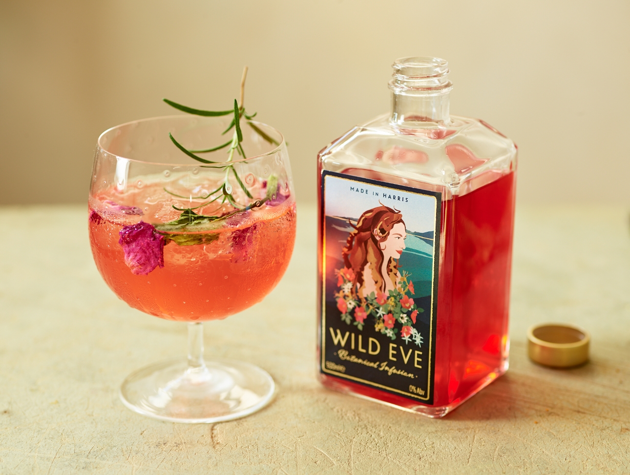 bottle of red liquid on a table next to a non alcoholic cocktail