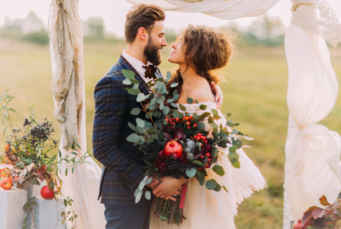 bride and groom embrace under an arch outdoors