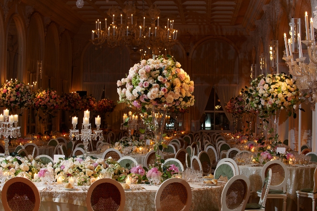 grand room in a castle with huge luxe floral displays candelabra and loads of tables for guests
