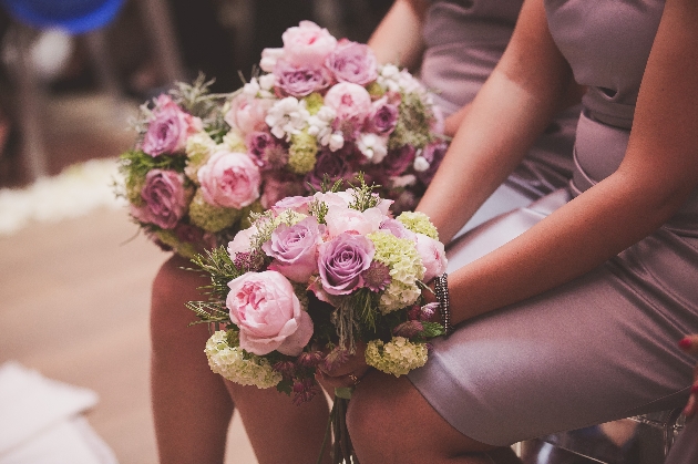 bridesmaids in purple dresses sat down holding flowers