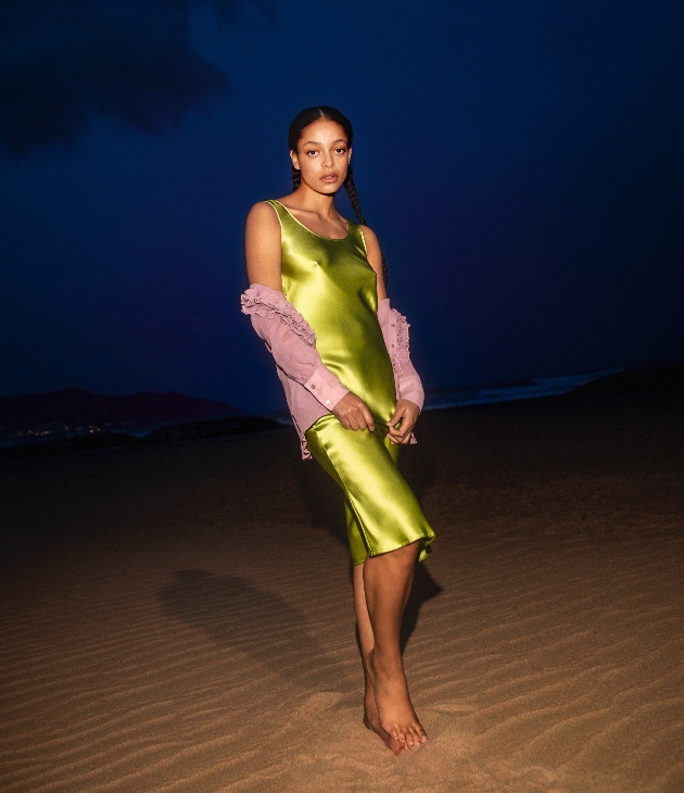 Kesewa Aboah wears green dress from the Whistles x Hai collection at night on the beach