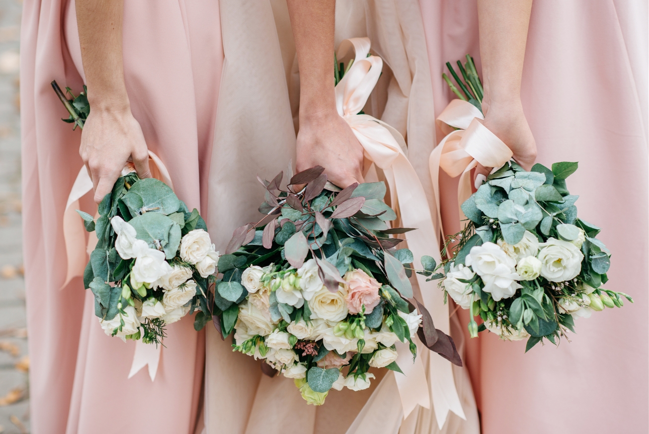bride and bridesmaids holding their bouquets with their arms dropped down, white and pink rose bouquets
