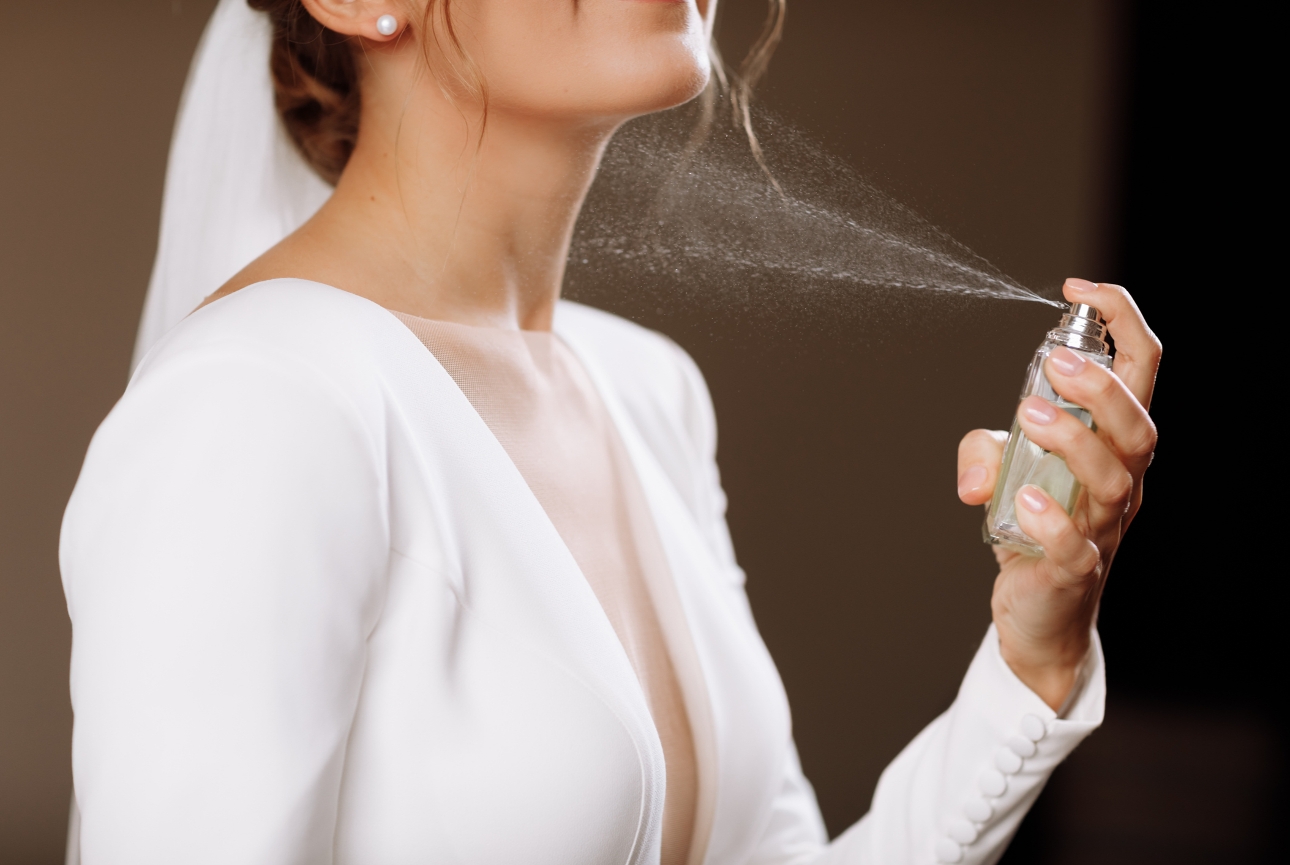 bride spritzing herself with a perfume bottle