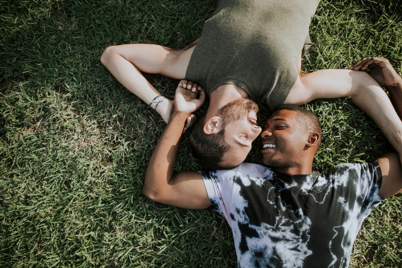 two men laying don on the grass hugging