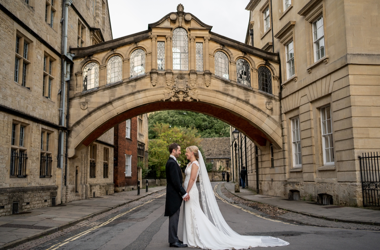 coupl elooking at eachother in wedding attire in the street with old building behind them