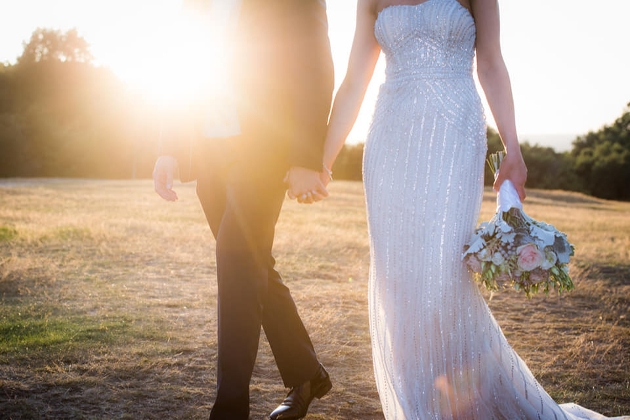 bride and groom walking in a field bride holding bouquet