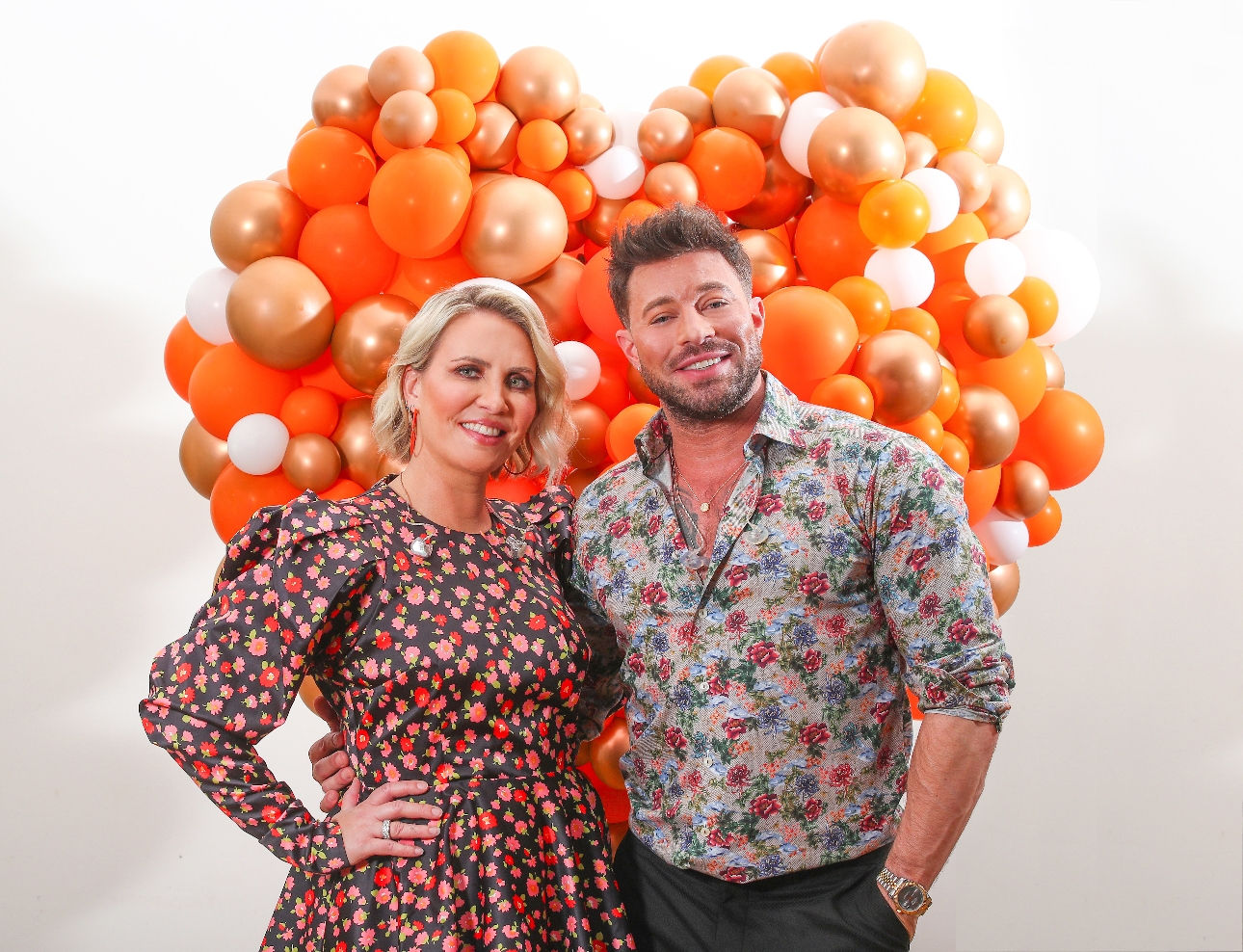 Claire Richards & Duncan James standing in front of orange balloons