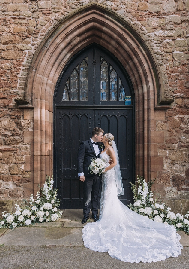 Couple stand infront of church doors