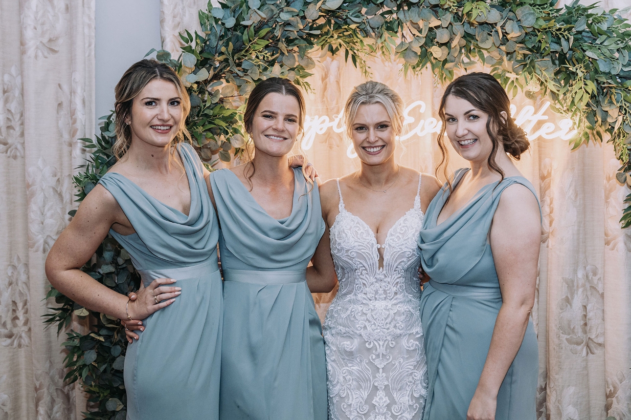 Bride and bridesmaids in front of neon sign