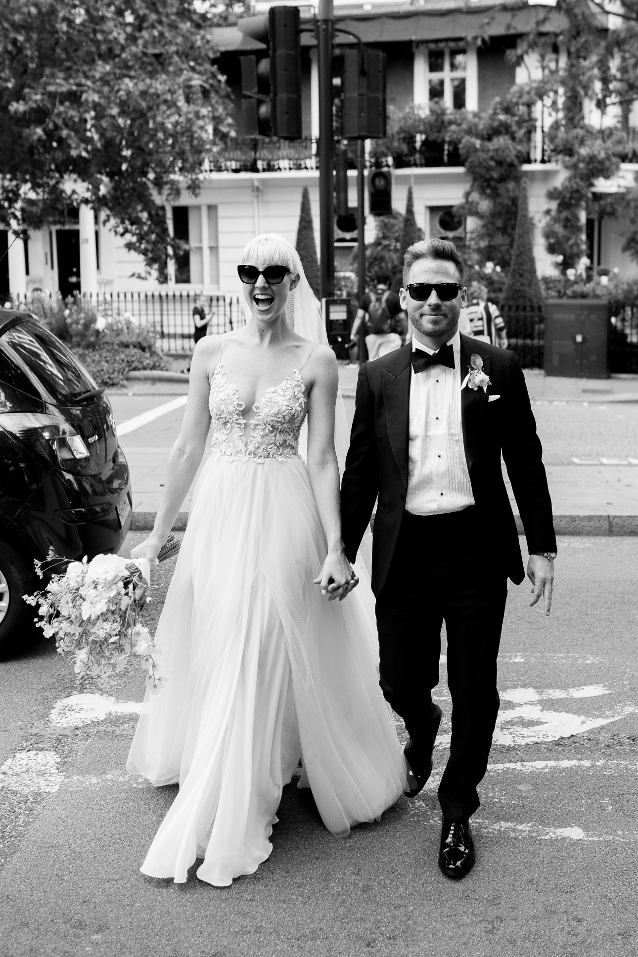 modern couple in wedding attire walking down london road in sunglasses