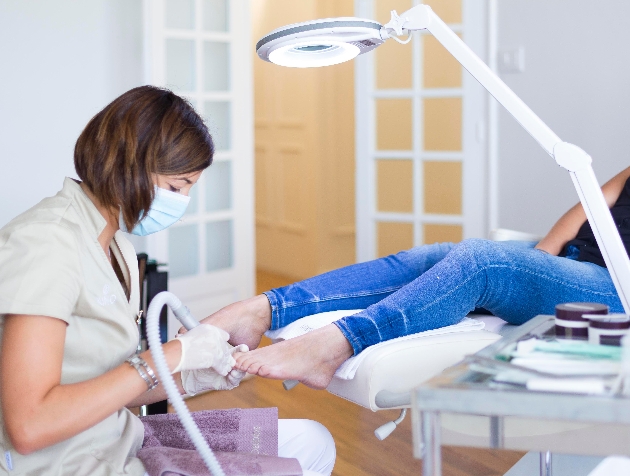 podiatrist from Margaret Dabbs works on someone's feet in clinic with electrical tool