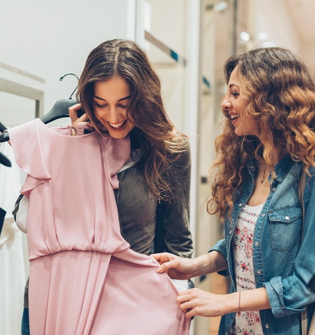 two women in shop looking at pink dress