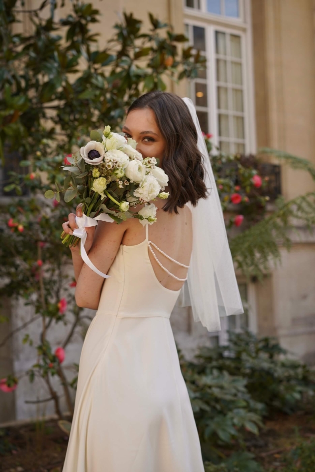 model in ivory simple dress with two rows of peals on the back. 